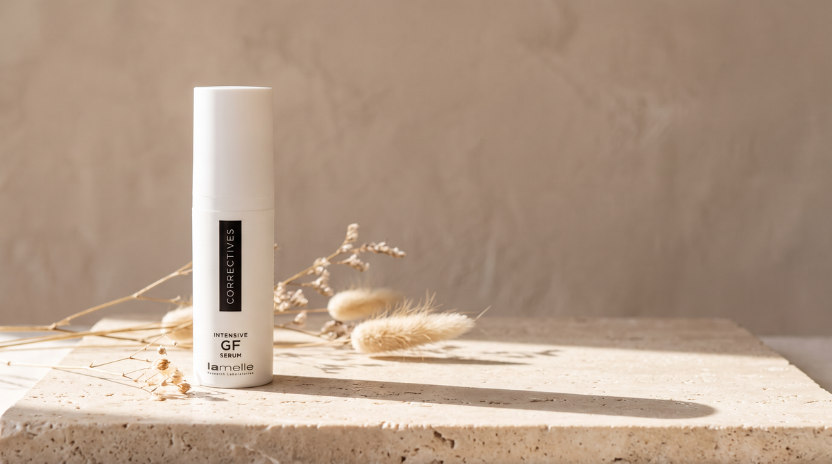 Lamelle Intensive GF Serum white pump bottle on a travertine plinth with dried grasses in soft daylight