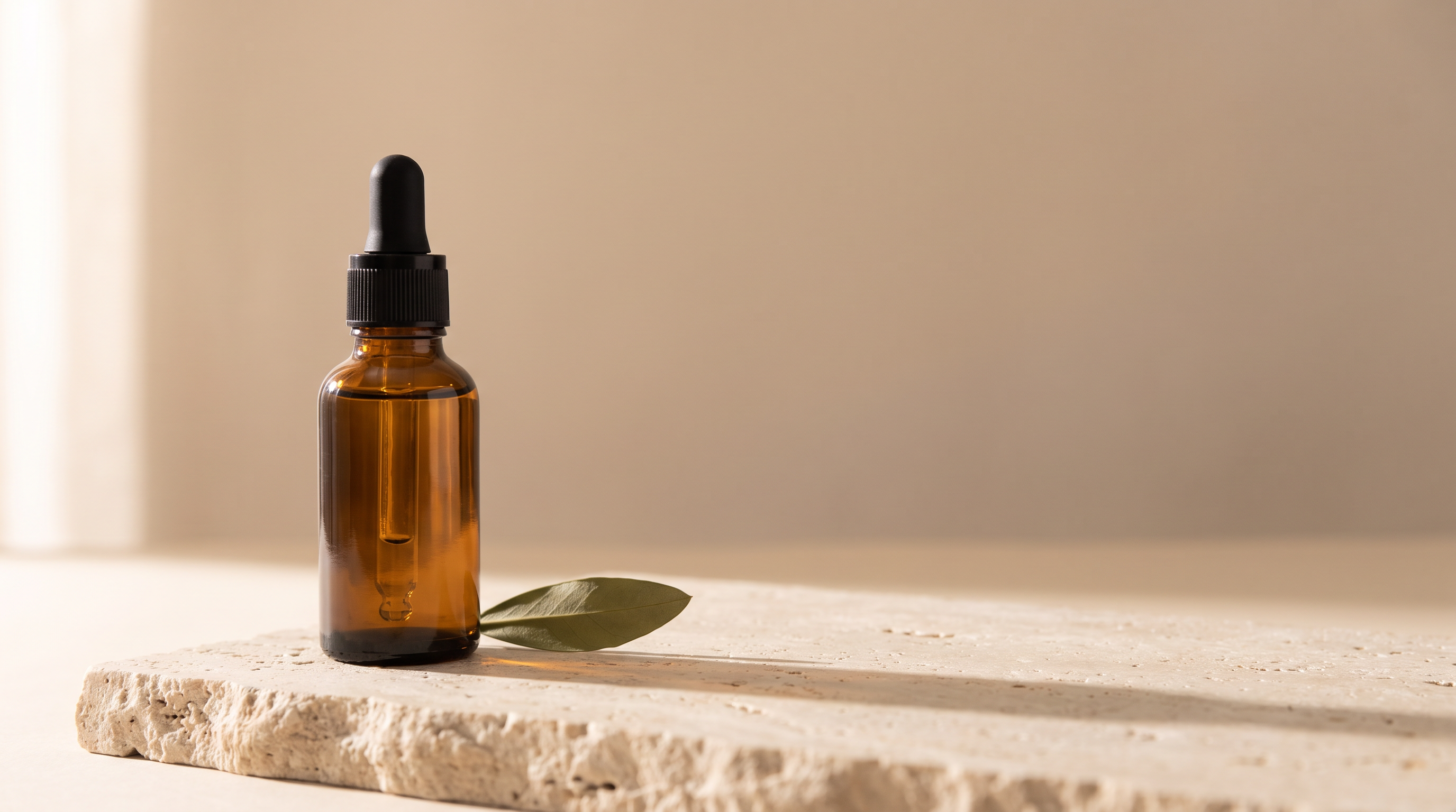 A single amber dropper bottle on a travertine stone slab in soft morning light