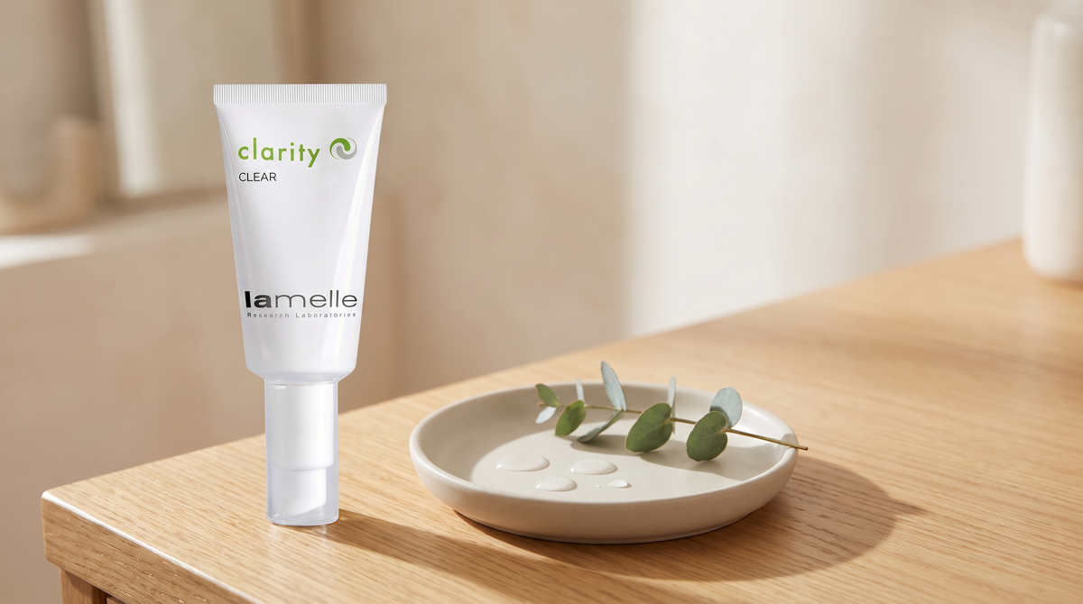 Lamelle Clarity Clear on a honey-toned wood surface with a ceramic dish, water droplets and eucalyptus